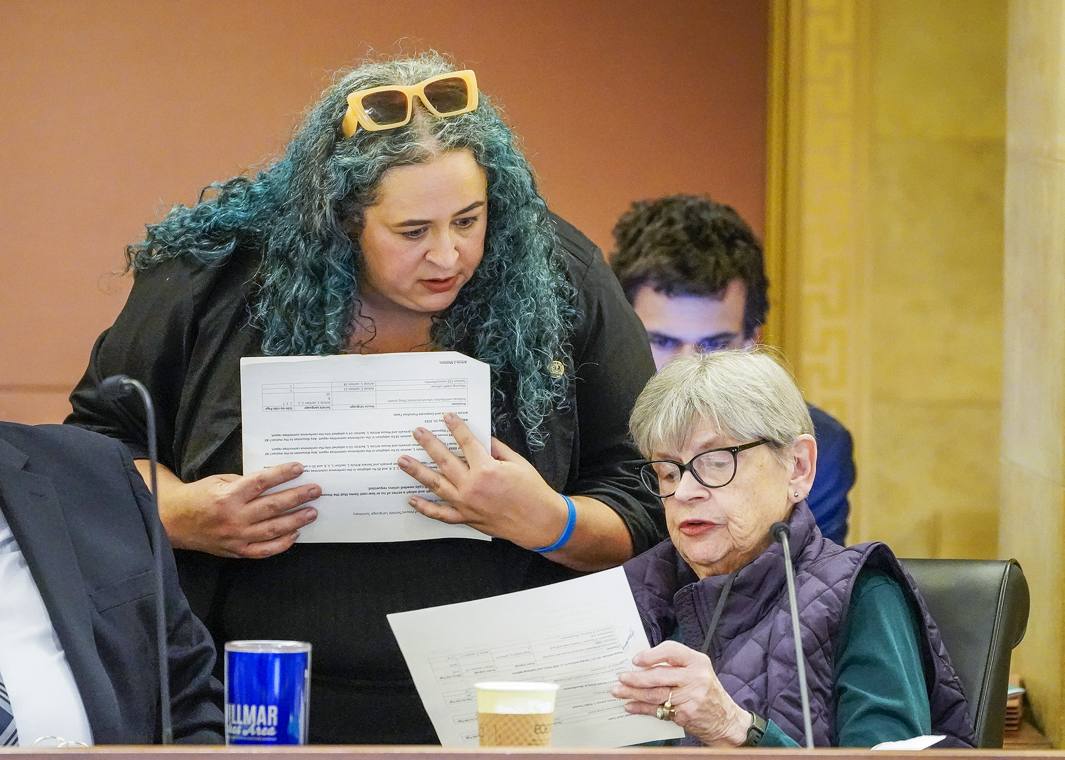 Rep. Aisha Gomez and Sen. Ann Rest confer before gaveling in the May 10 meeting of the taxes conference committee. (Photo by Andrew VonBank)